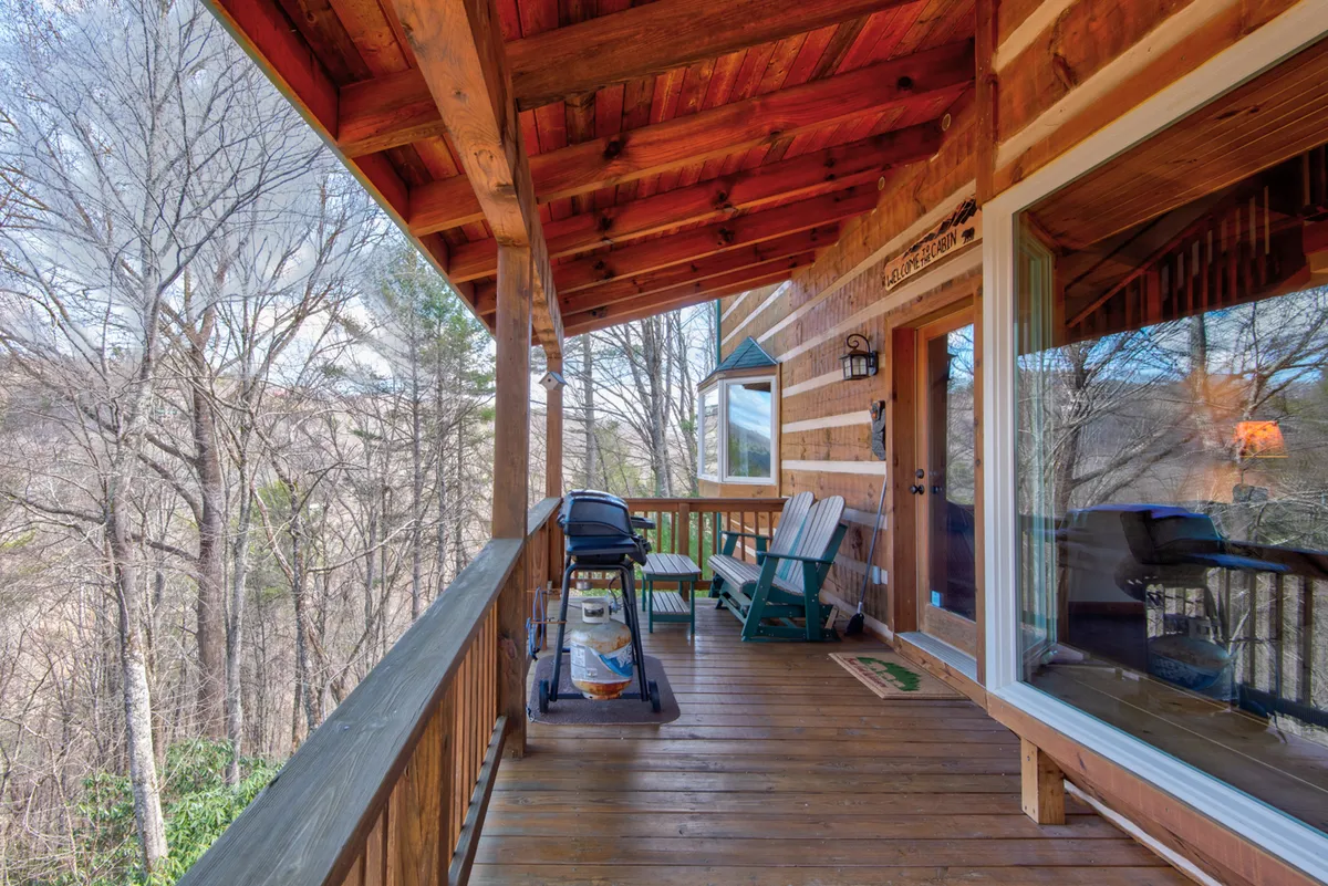 A tranquil deck scene with rocking chairs and a decorative lantern, surrounded by trees. The setting feels serene and perfect for quiet mornings or evenings immersed in nature.