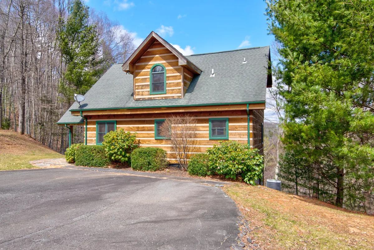 The image captures the log cabin surrounded by lush trees, highlighting its seclusion and the beauty of the mountain environment. The earthy green accents on the cabin blend with the landscape, and the ample outdoor space hints at opportunities for wildlife watching and peaceful strolls, as mentioned in the section.